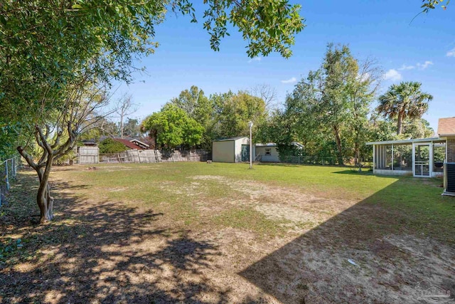 view of yard featuring an outbuilding, a sunroom, a fenced backyard, and a storage unit