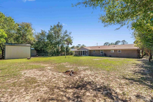 view of yard with a storage shed, fence, a sunroom, and an outbuilding