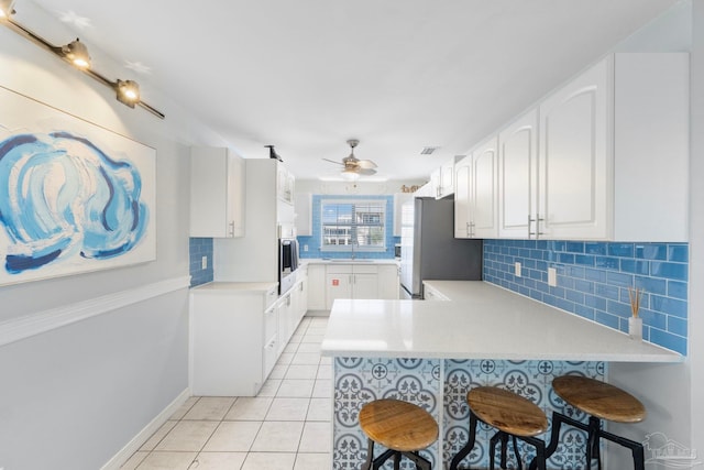 kitchen featuring white cabinetry, kitchen peninsula, and a kitchen bar