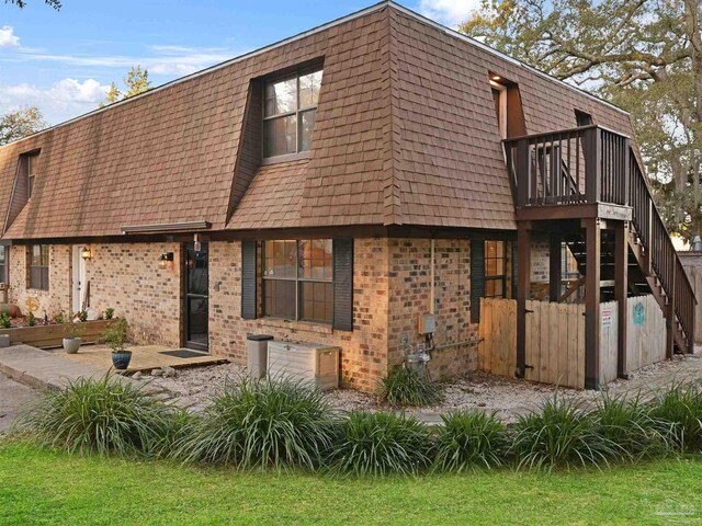 2701 E De Soto St, Pensacola, FL 32503 - view of front of house with mansard roof, brick siding, a deck, and stairs