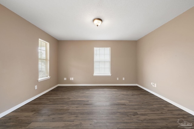 spare room with dark hardwood / wood-style floors and a textured ceiling