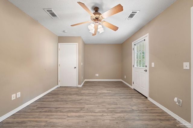 spare room featuring wood-type flooring, ceiling fan, and a textured ceiling