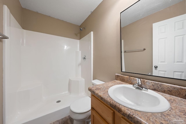 bathroom featuring walk in shower, vanity, a textured ceiling, and toilet