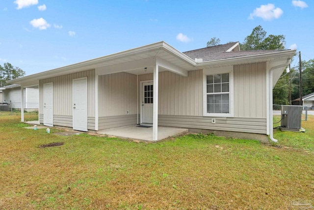 rear view of house with central AC unit, a lawn, and a patio