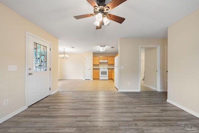 unfurnished living room featuring dark wood-type flooring and ceiling fan with notable chandelier