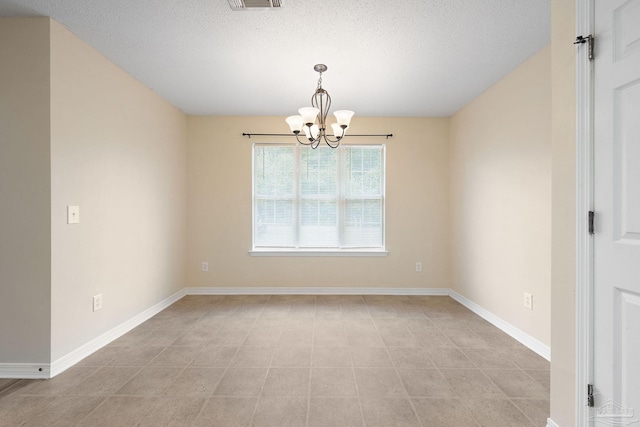 spare room featuring a notable chandelier and a textured ceiling