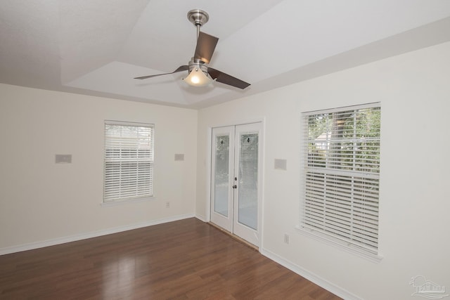 empty room featuring dark hardwood / wood-style flooring, a raised ceiling, ceiling fan, and french doors