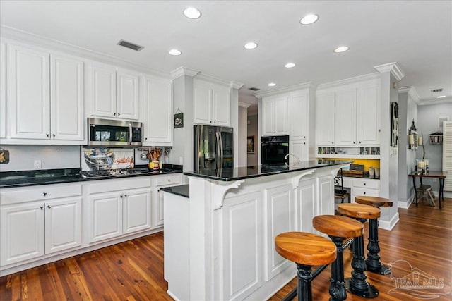 kitchen featuring dark countertops, white cabinets, ornamental molding, stainless steel appliances, and recessed lighting