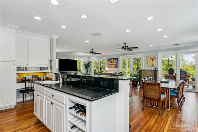 kitchen featuring dark countertops, a sink, ornamental molding, recessed lighting, and a wealth of natural light
