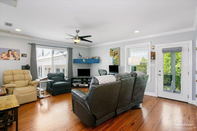 living room featuring plenty of natural light, ornamental molding, and a ceiling fan