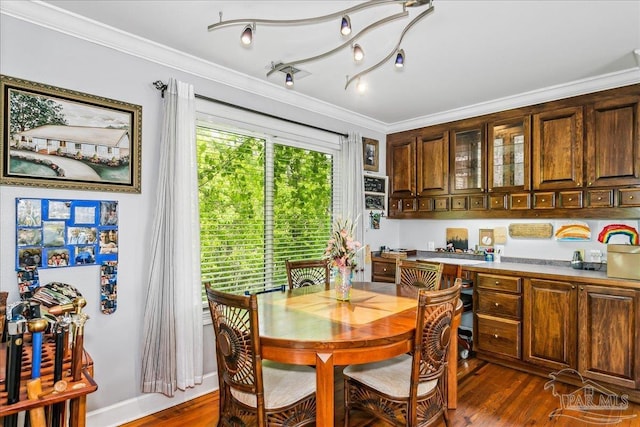 dining space with crown molding, dark wood finished floors, and baseboards