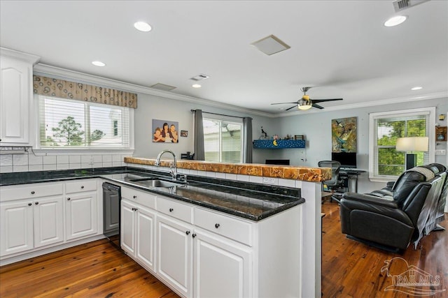 kitchen featuring dark wood finished floors, dishwasher, a sink, a peninsula, and open floor plan