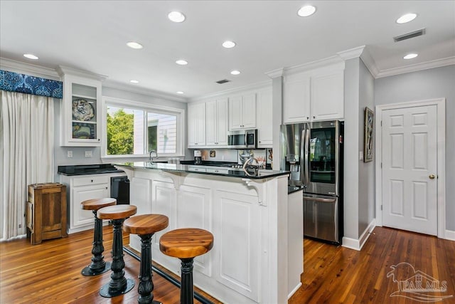 kitchen featuring a kitchen bar, visible vents, appliances with stainless steel finishes, white cabinets, and ornamental molding