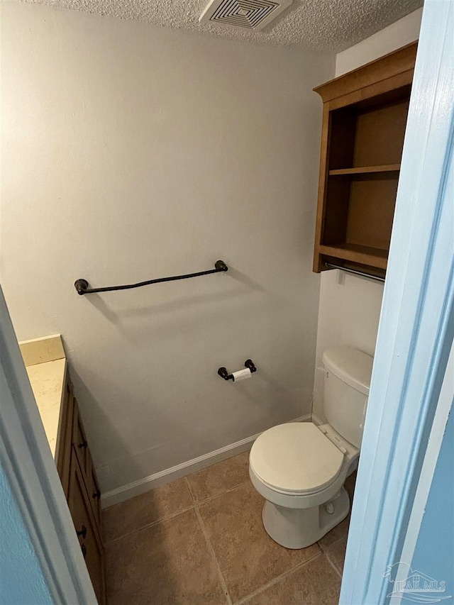 bathroom featuring vanity, toilet, a textured ceiling, and tile patterned floors