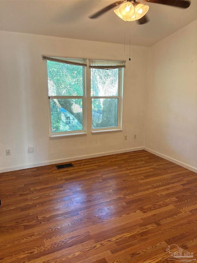 spare room featuring ceiling fan, dark hardwood / wood-style flooring, and a healthy amount of sunlight