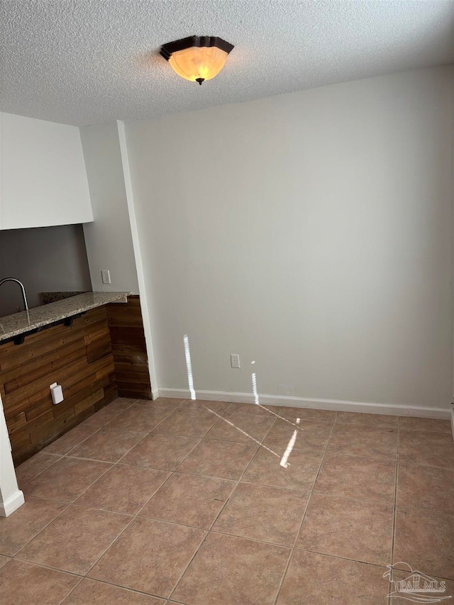 unfurnished dining area featuring a textured ceiling and tile patterned floors