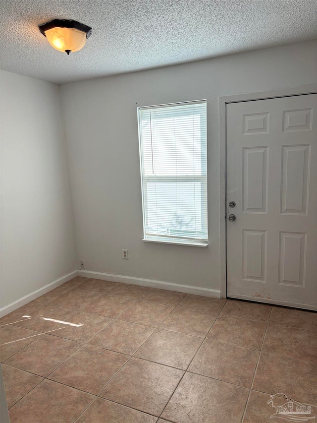 entryway with a textured ceiling and light tile patterned floors