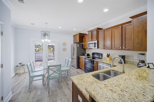 kitchen with stainless steel appliances, decorative backsplash, sink, light stone countertops, and light hardwood / wood-style floors