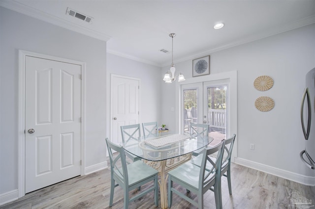 dining space featuring crown molding, french doors, a notable chandelier, and light hardwood / wood-style floors