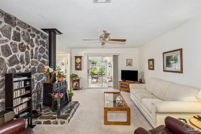 carpeted living room with a wood stove, a textured ceiling, and ceiling fan