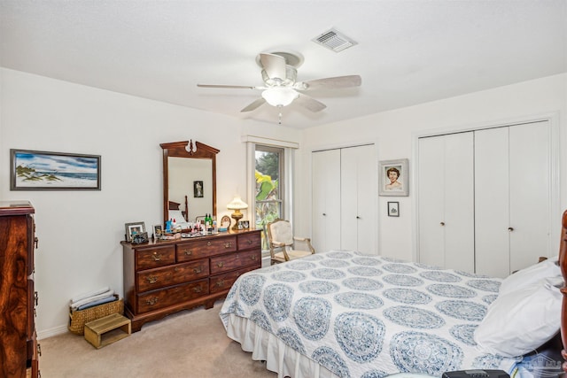 bedroom with multiple closets, light colored carpet, and ceiling fan