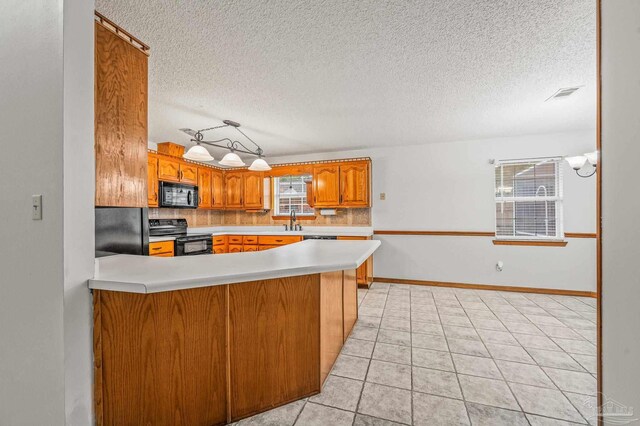 4420 Bellwood Cir, Pace, FL 32571 - kitchen with black appliances, brown cabinets, light countertops, a textured ceiling, and backsplash
