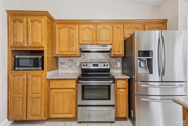 5833 Pebble Ridge Dr, Milton, FL 32583 - kitchen with appliances with stainless steel finishes, under cabinet range hood, decorative backsplash, light stone counters, and brown cabinetry