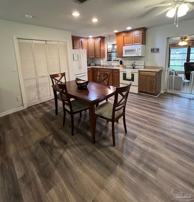 dining room featuring sink, ceiling fan, dark wood-type flooring, and a textured ceiling