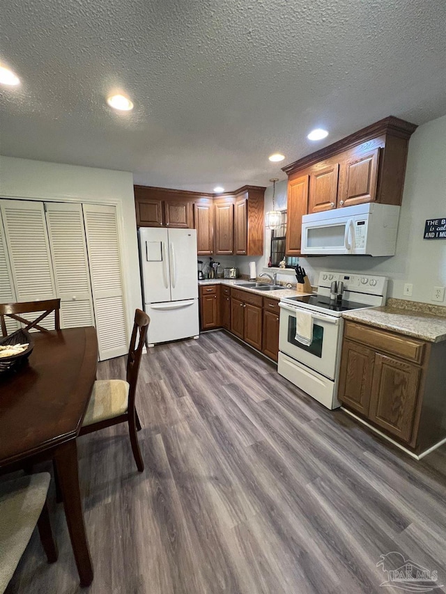 kitchen featuring white appliances, sink, pendant lighting, a textured ceiling, and dark hardwood / wood-style floors