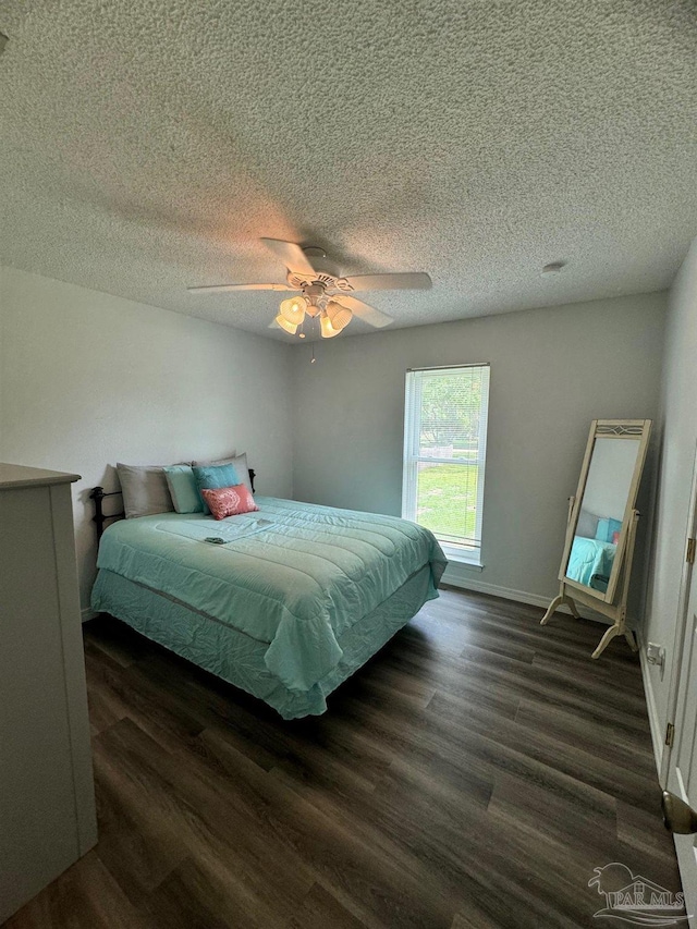 bedroom with dark hardwood / wood-style flooring, ceiling fan, and a textured ceiling