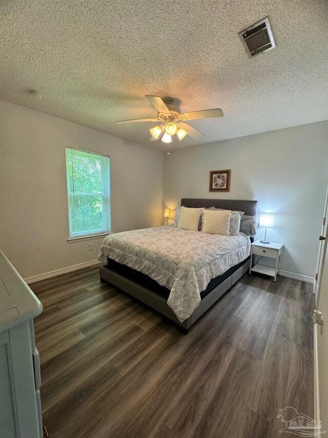 bedroom with a textured ceiling, ceiling fan, and dark hardwood / wood-style floors