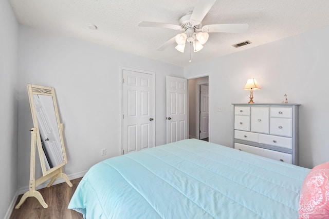 bedroom with a textured ceiling, hardwood / wood-style flooring, and ceiling fan