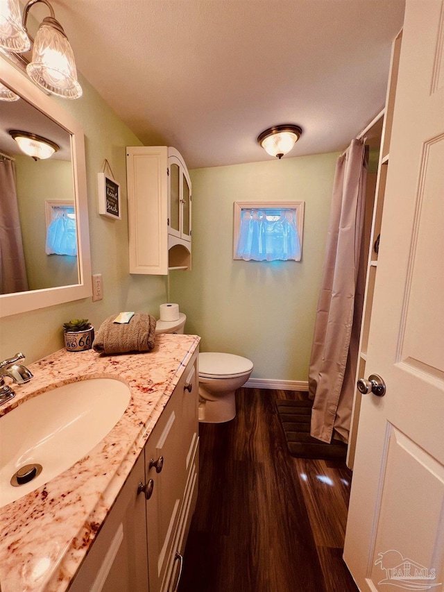 bathroom with toilet, hardwood / wood-style flooring, walk in shower, and vanity