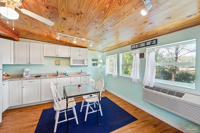 kitchen with light hardwood / wood-style flooring, rail lighting, wood ceiling, sink, and white cabinetry