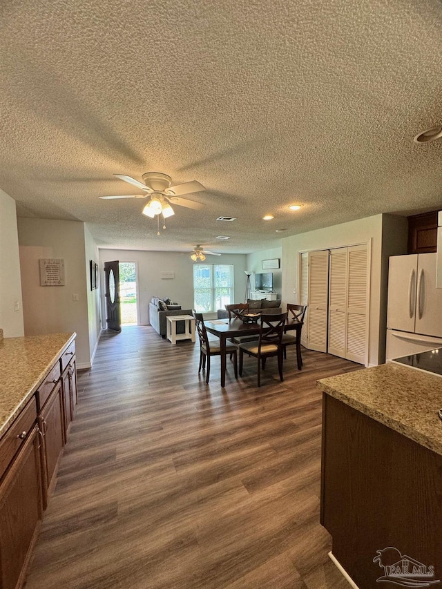 dining room featuring dark hardwood / wood-style flooring, ceiling fan, and a textured ceiling