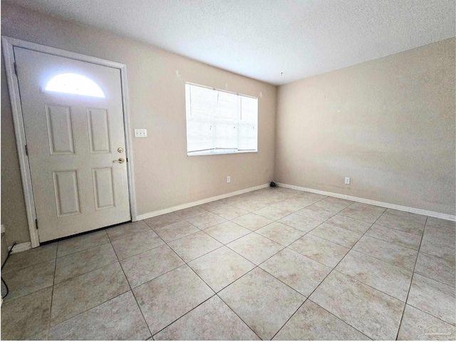 foyer with baseboards, a textured ceiling, and light tile patterned flooring