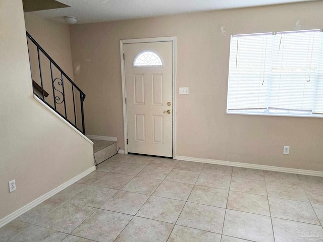 entryway featuring light tile patterned flooring, baseboards, and stairs