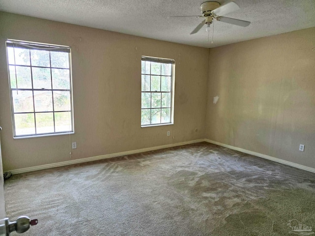 empty room with a textured ceiling, carpet flooring, a ceiling fan, and baseboards