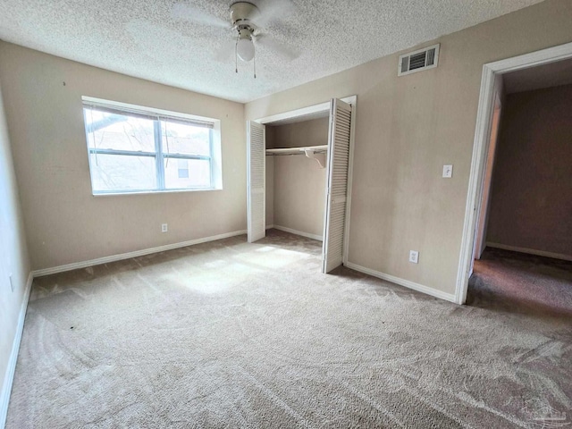 unfurnished bedroom featuring a closet, visible vents, carpet flooring, a textured ceiling, and baseboards