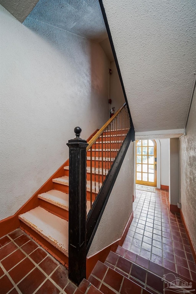 2007 E Gadsden St Unit 105, Pensacola, FL 32501 - staircase with a textured ceiling, a textured wall, lofted ceiling, tile patterned floors, and baseboards