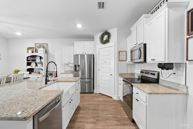 5722 Conley Ct, Pace, FL 32571 - kitchen with appliances with stainless steel finishes, wood finished floors, a sink, white cabinetry, and backsplash