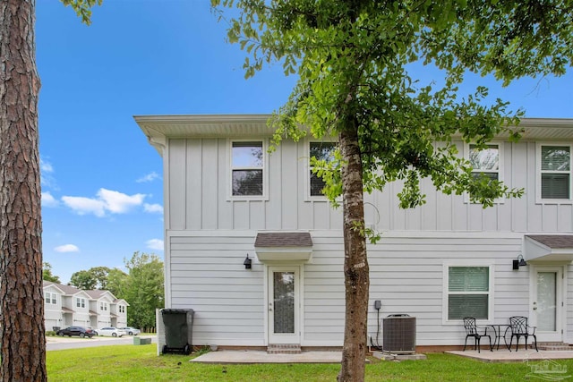 rear view of property featuring a lawn, central air condition unit, and a patio area