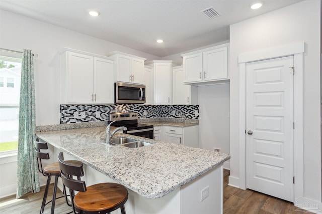 kitchen featuring white cabinetry, decorative backsplash, stainless steel appliances, and kitchen peninsula