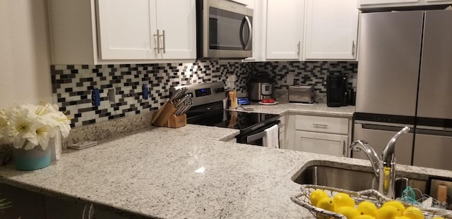 kitchen with light stone countertops, appliances with stainless steel finishes, sink, and white cabinets