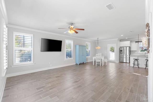 unfurnished living room featuring ceiling fan, light wood-type flooring, and ornamental molding