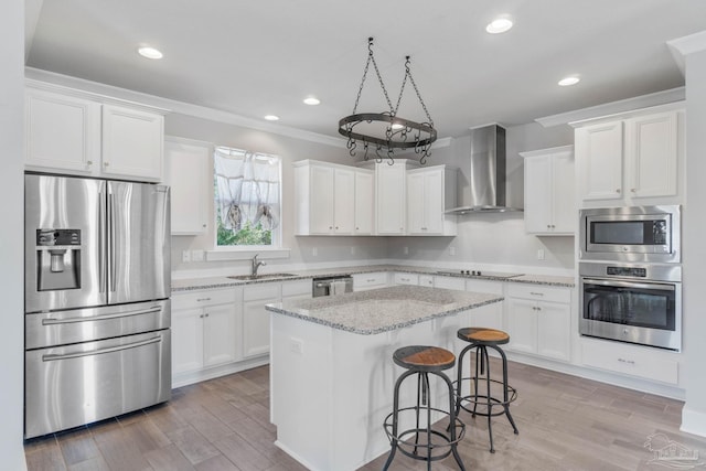 kitchen featuring white cabinets, sink, wall chimney exhaust hood, a kitchen island, and stainless steel appliances