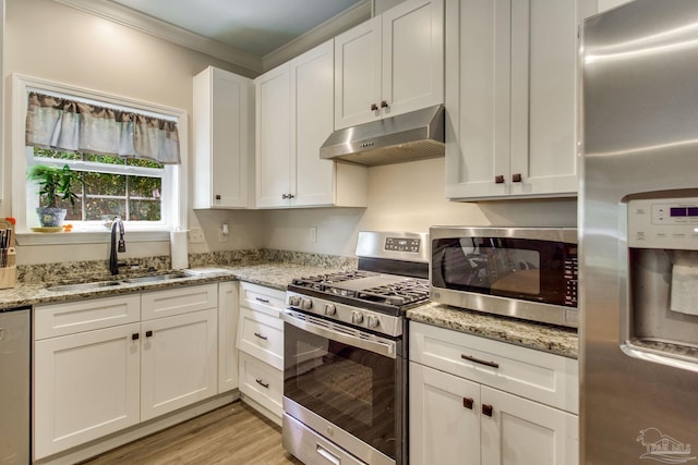 kitchen with ornamental molding, under cabinet range hood, white cabinets, a sink, and stainless steel appliances