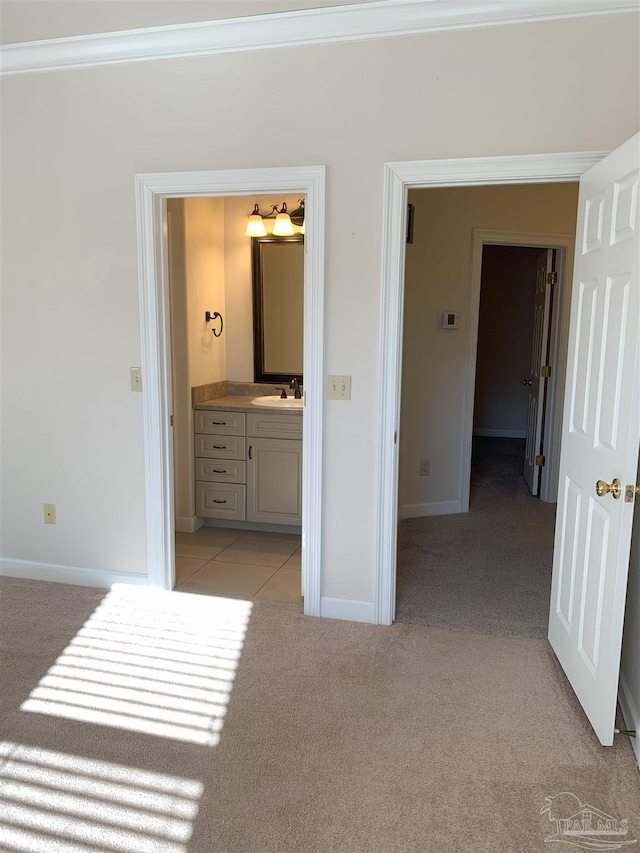 bedroom featuring crown molding, sink, light colored carpet, and ensuite bathroom