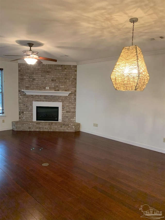 unfurnished living room with crown molding, ceiling fan, a fireplace, and dark hardwood / wood-style flooring