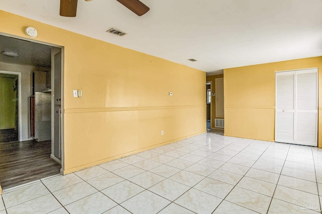 spare room with a ceiling fan, visible vents, and light tile patterned floors